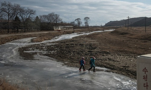 Hai học sinh đi bộ trên một dòng sông đóng băng tới trường gần Raksan hôm 21/11. Ảnh: ATI.