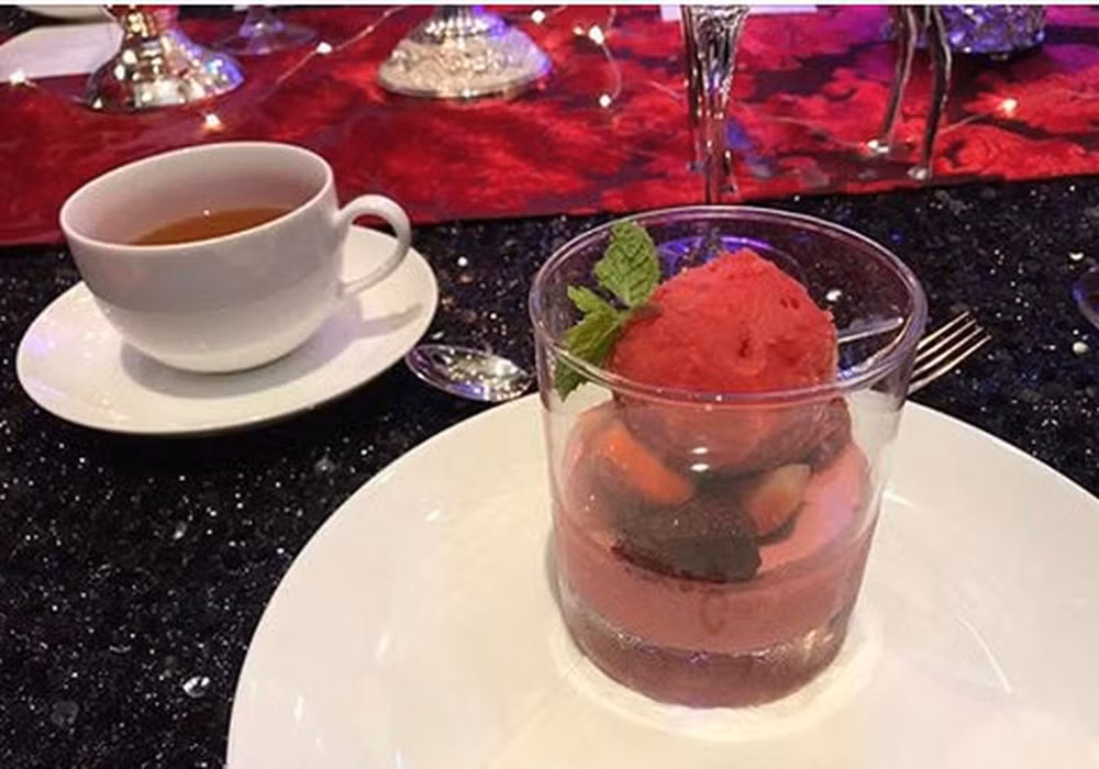 Món tráng miệng: Panna cotta kem blackcurrant (quả lý chua đen) và trà nóng. Lý chua đen (hay blackcurrant) là một loại cây bụi bản địa của một số vùng Trung Âu, Bắc Âu và Bắc Á. Cây ưa lạnh, ra nhiều quả thành chùm dọc thân vào mùa hè. Quả lý chua đen giàu vitamin C, chất dinh dưỡng và chất chống oxy hóa. Trong tiệc cưới, đây là nguyên liệu làm thành món kem, phía dưới là panna cotta kiểu Italy.