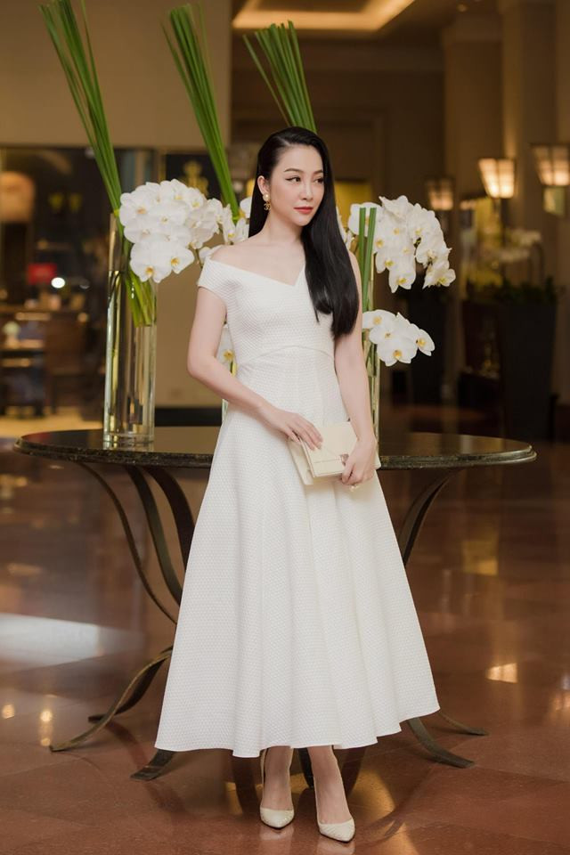 Kiểu đầm trắng lệch vai nữ tính được Linh Nga phối với giày trắng và túi xách trắng cực kỳ tinh tế và sang chảnh.