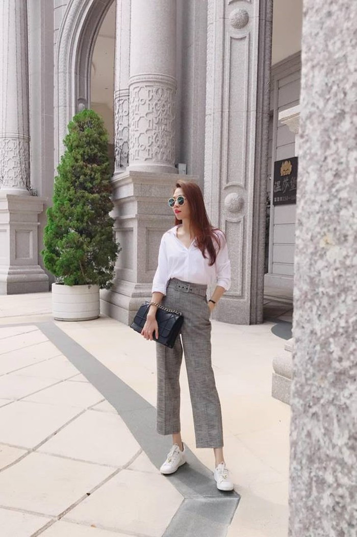 Cô kết hợp sơ mi trắng cùng quần xám cạp cao và giày thể thao trắng rất phong cách.