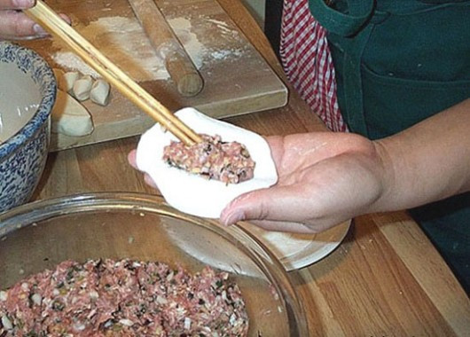 Gói bánh: Đặt miếng bột trên mặt phẳng và cho nhân thịt vào giữa, thêm 1 quả trứng cút rồi xếp vỏ bánh lại, kẹp mép theo hình vắt chéo sao cho mép bột dính lại với nhau và đẹp mắt là được. 