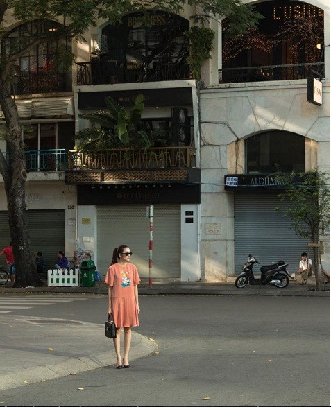 Hà Tăng chọn chiếc váy xuông màu cam nữ tính khi đi dạo phố.