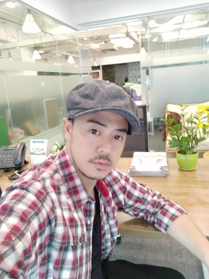 Bố Quốc thường diện áo phông khoác sơ mi kẻ bụi bặm phối với mũ nồi.