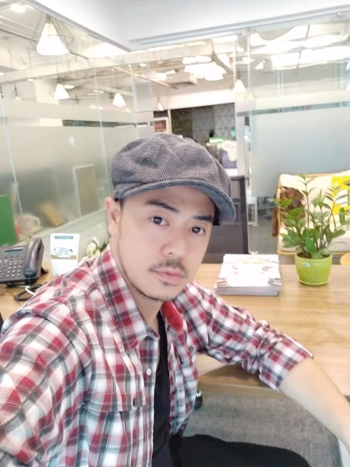 Bố Quốc thường diện áo phông khoác sơ mi kẻ bụi bặm phối với mũ nồi.