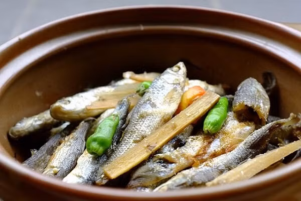 Đầu cá kho với mía đầu cá sẽ rất mềm, có thể ăn được. Cây mía, róc bỏ vỏ, chẻ nhỏ để dưới đáy nồi, rồi cho cá, nước dừa xiêm vào ngập xâm xấp, để lên bếp đun với ngọn lửa riu riu cho đến khi nước dừa rút cạn, cá chín, xương mềm rục là được. Cuối cùng, người ta cho thêm vào một ít tiêu xay, vài trái ớt hiểm chín để hoàn thành món ăn. Ảnh: Internet.