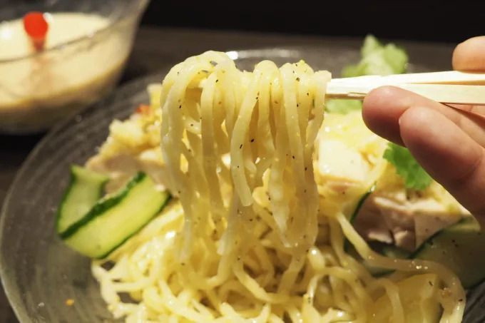 Món mì trà sữa này được phục vụ với 2 phần. Bát mì bao gồm mấy lát thịt gà, dưa chuột, hành lá, chanh cắt múi, rau sống, mì sợi, nhìn khá ngon mắt và tươi mát. Phần còn lại là một bát nước dùng nhưng thay vì phiên bản truyền thống, món ăn này chuẩn bị một bát nước dùng béo ngậy, màu kem, với hương vị trà sữa và một ít trân châu dẻo.