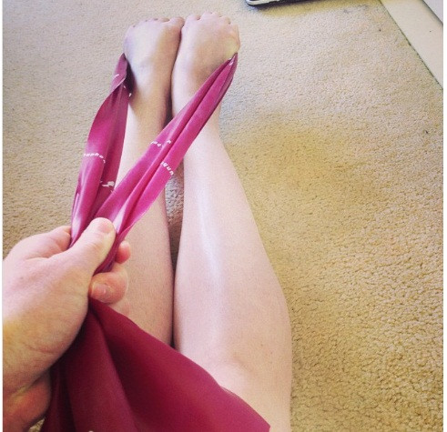 Dùng dây cao su duỗi chân để giúp giảm căng thẳng và đau.