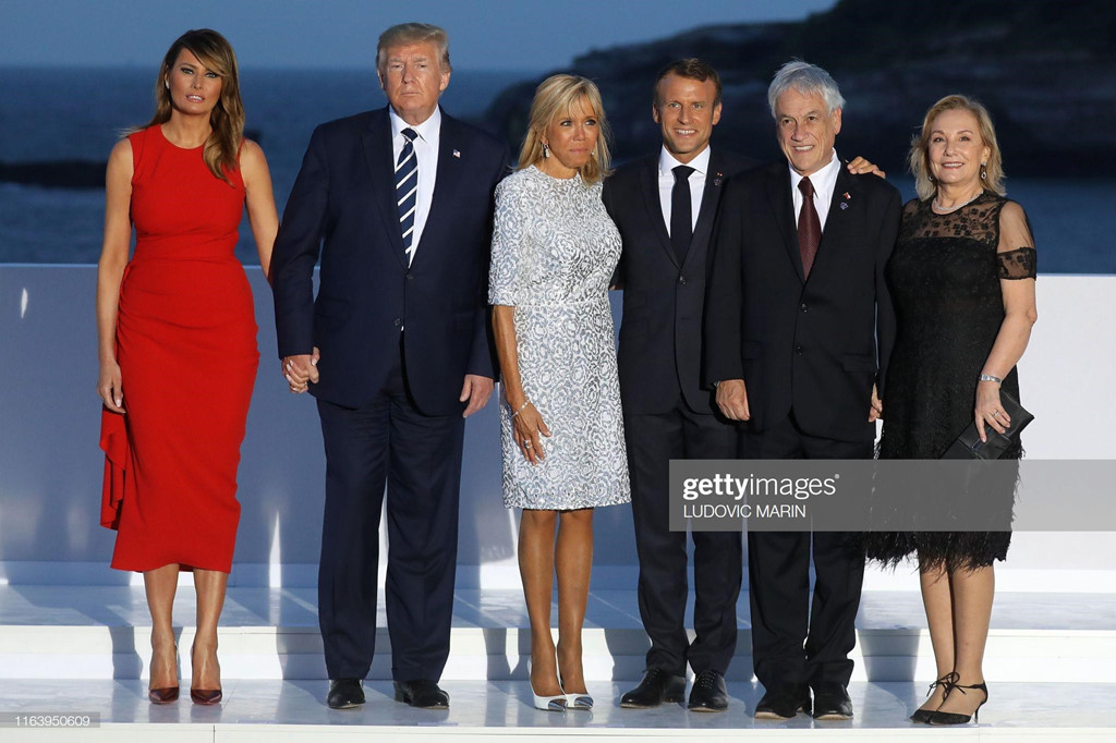 Trong các bức ảnh chụp trước ngọn hải đăng ở Biarritz, Melania hoàn toàn nổi bật khi diện váy đỏ có thiết kế ôm sát body, đẹp lấn át trước dàn phu nhân của các nhà lãnh đạo khác.