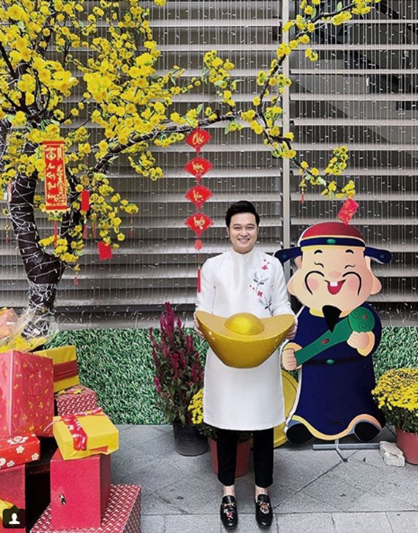 Ca sĩ Quang Vinh vẫn vô cùng trẻ trung với áo dài màu trắng thêu hoa đơn giản, phối cùng quần âu đen và giày hiệu.