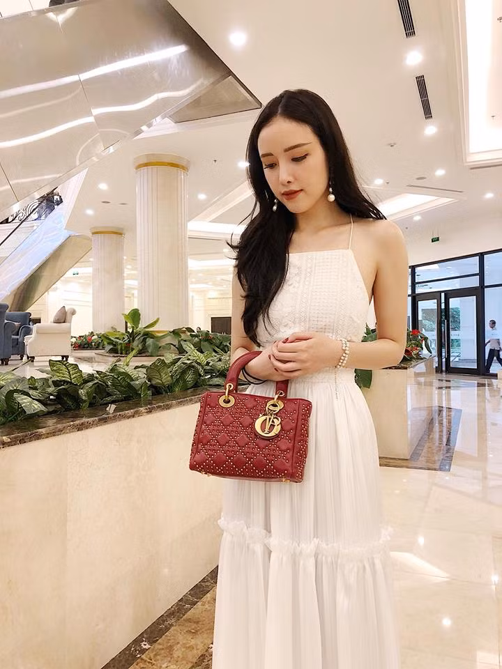Mai Ngọc Phượng mặc chiếc đầm trắng hai dây đằm thắm mix với túi xách hàng hiệu màu đỏ sành điệu.