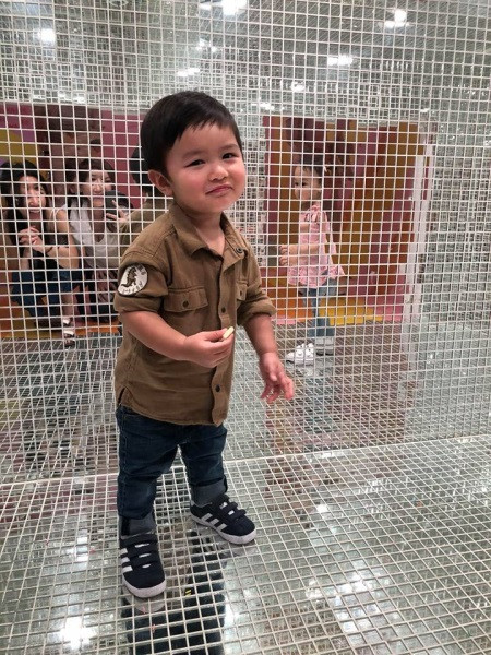 Cậu bé có phong cách thời trang khỏe khoắn pha chút bụi bặm với áo sơ mi thô nâu xắn tay, quần bò và giày thể thao.