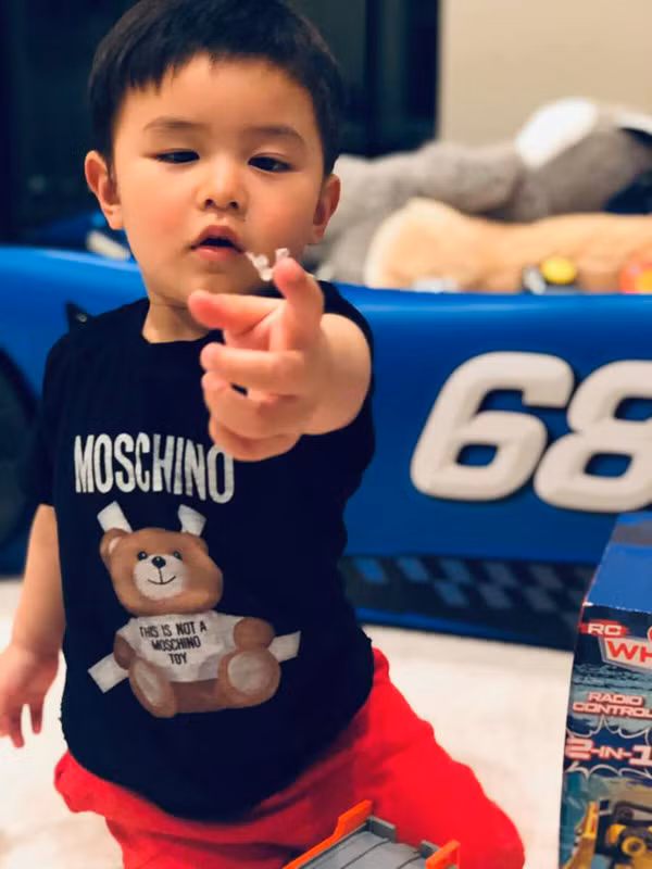Cậu bé 2 tuổi ăn mặc sành điệu và không ít món đồ là hàng hiệu như chiếc áo hiệu Moschino có giá vài triệu đồng.