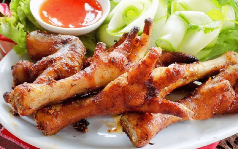 Chân gà nướng: Có tên trong bản đồ ăn vặt từ rất lâu về trước, chân gà nướng xứng đáng được coi là "anh cả" trong gia đình các món ăn từ chân gà. Dù nướng sa tế, mật ong, hay muối ớt, món ăn đều gây ấn tượng bởi màu sắc bắt mắt và hương vị thơm ngon khó cưỡng.