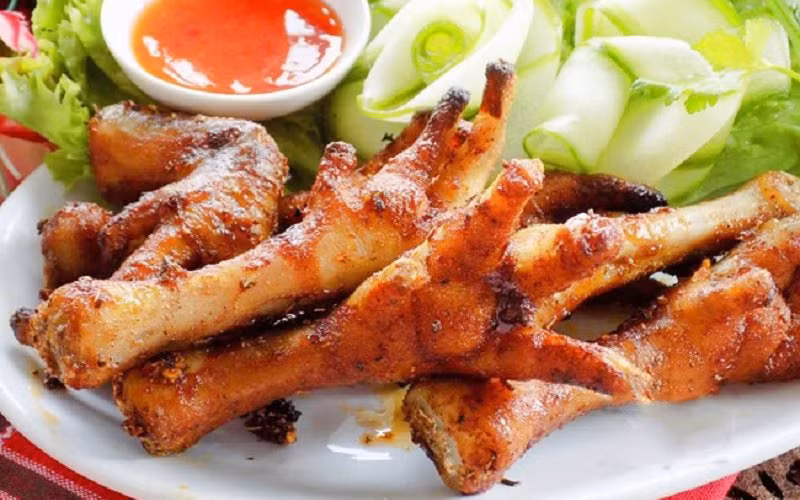 Chân gà nướng: Có tên trong bản đồ ăn vặt từ rất lâu về trước, chân gà nướng xứng đáng được coi là "anh cả" trong gia đình các món ăn từ chân gà. Dù nướng sa tế, mật ong, hay muối ớt, món ăn đều gây ấn tượng bởi màu sắc bắt mắt và hương vị thơm ngon khó cưỡng.