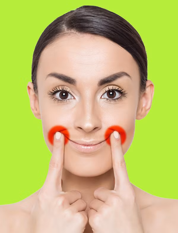 Mỉm cười, đặt hai ngón tay trỏ lên điểm trên cùng của khoé môi, đẩy da lên cao để hạn chế nếp nhăn, cải thiện tình trạng da chảy xệ.