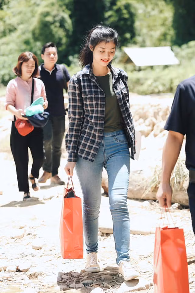 Khi đi từ thiện, người đẹp chọn quần jean, áo phông và khoác áo sơ mi kẻ năng động.