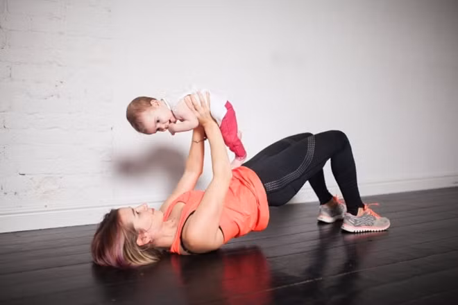 Nâng cao hông: Nằm ngửa trên sàn, hai tay ôm em bé đưa thẳng trước mặt, đầu gối gập. Nâng hông cao 10 lần.