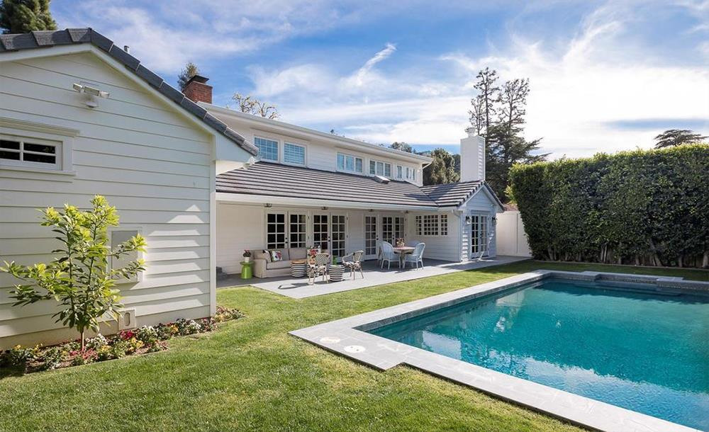 Bể bơi ngoài trời được bao quanh bởi bãi cỏ và vườn hoa tươi tốt.