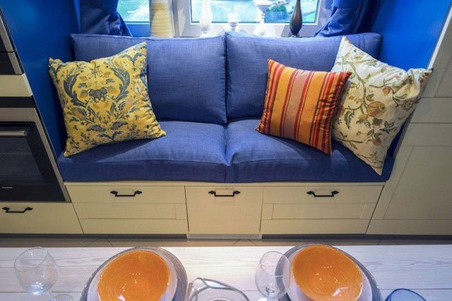 Chiếc ghế đa năng tích hợp vào chiếc tủ, ngay sát cửa sổ, kê thêm một bộ nệm và gối là có một chiếc ghế dài, tạo nên điểm nhấn cho gian bếp.