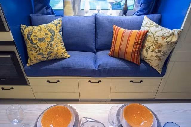 Chiếc ghế đa năng tích hợp vào chiếc tủ, ngay sát cửa sổ, kê thêm một bộ nệm và gối là có một chiếc ghế dài, tạo nên điểm nhấn cho gian bếp.