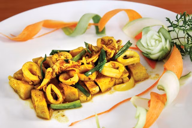 Phi thơm tỏi, cho mít luộc xé vào xào thơm. Thêm bột nghệ, nước mắm, đường, hạt nêm, hạt tiêu vào xào đều tay. Khi mít thấm gia vị và nước sánh lại thì cho mực và hành tây vào xáo. Mực chín thì cho hành lá, húng quế vào và tắt bếp. Cho mít non xào mực ra đĩa và rắc hạt tiêu lên trên.