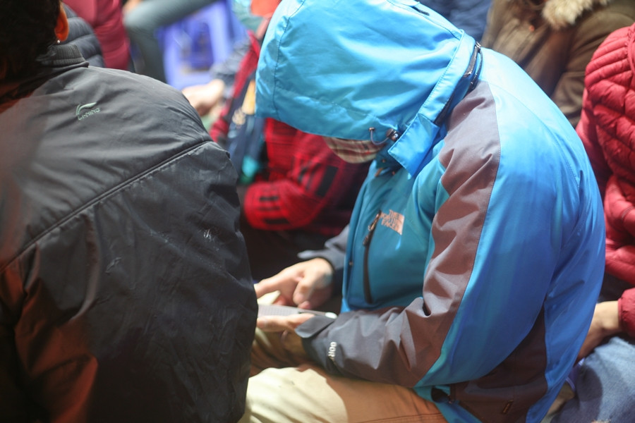 Khách hàng tranh thủ xem điện thoại để "giết thời gian" trong lúc chờ đợi một cửa hàng vàng trên đường Trần Nhân Tông mở bán (6h10 cùng ngày).