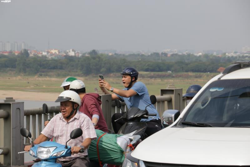 Nhiều người ngồi trên xe máy, mở điện thoại ghi lại sự việc diễn ra.
