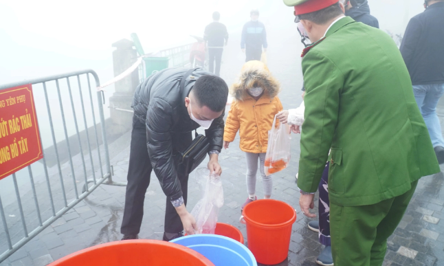 Nhiều bạn nhỏ cũng theo bố mẹ đi thả cá chép, tìm hiểu về phong tục cổ truyền dân gian. (Ảnh Sức Khỏe và Đời Sống) 