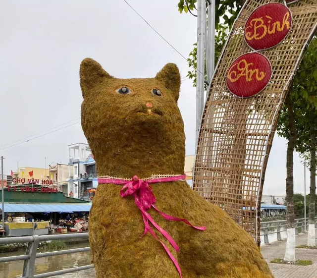 Mèo Tiền Giang được làm từ rơm rạ ép trông có vẻ khá lạ mắt. Tuy nhiên, cấu tạo khuôn mặt chú mèo khiến dân tình phải thắc mắc không biết đây là mèo hay chuột. Dù nhận được nhiều lời chê bai &#34;nhan sắc&#34; từ cộng đồng mạng, nhưng một số khác lại khá thích thú với khuôn mặt &#34;ngốc nghếch&#34; của linh vật mèo này. 