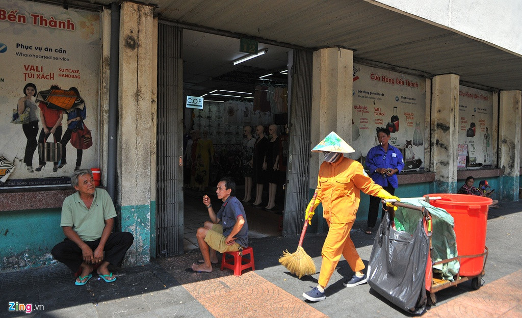 Ông Phục (bìa trái) và ông Hiệp ngồi nói chuyện với nhau tại một cửa ra vào chợ Bến Thành. 2 ông làm nghề chở hàng thuê bằng xe máy tại chợ. Nếu lúc trước các ông luôn bận bịu thì nay hoàn toàn trái ngược. Cả ngày 27/2, ông Phục và ông Hiệp chỉ chở được 2 cuốc xe hàng, thu nhập mấy chục nghìn đồng.