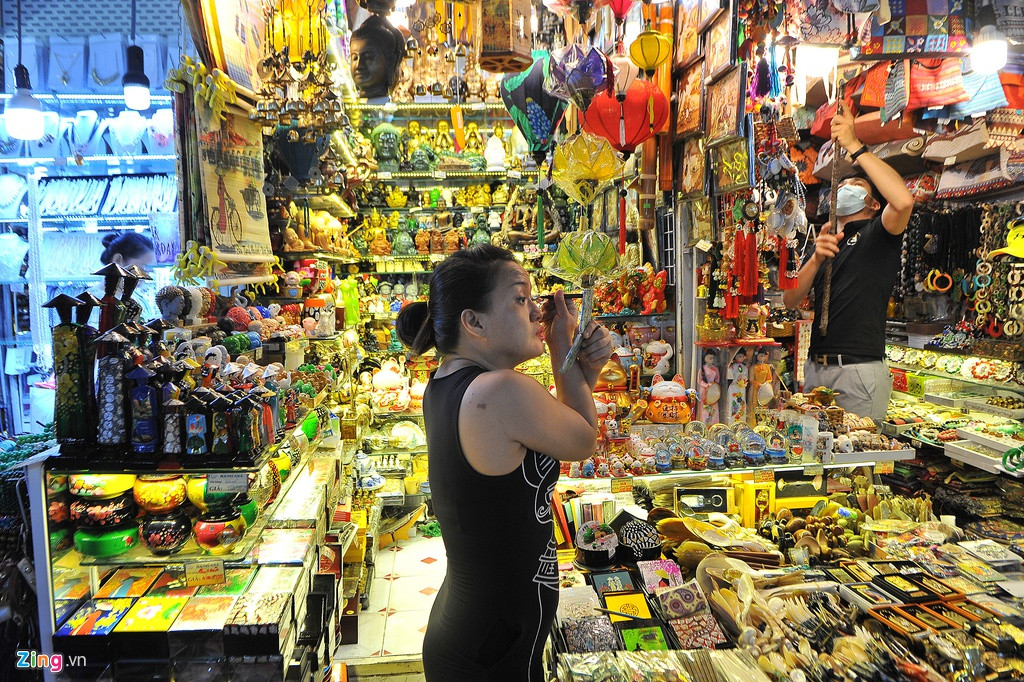 Hơn 10h sáng, một tiểu thương vẫn thảnh thơi trang điểm tại sạp bán đồ mỹ nghệ của mình. Được biết lúc trưa có dịch Covid-19, thời gian này thuộc khung giờ "cao điểm" buôn bán tại chợ, hoạt động mua bán diễn ra tất bật.