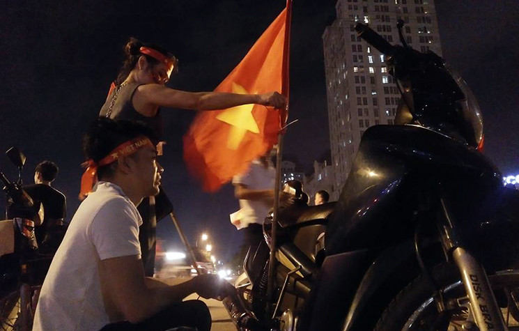 Đôi bạn trẻ mang theo cờ xuống đường Hà Nội ăn mừng chiến thắng.