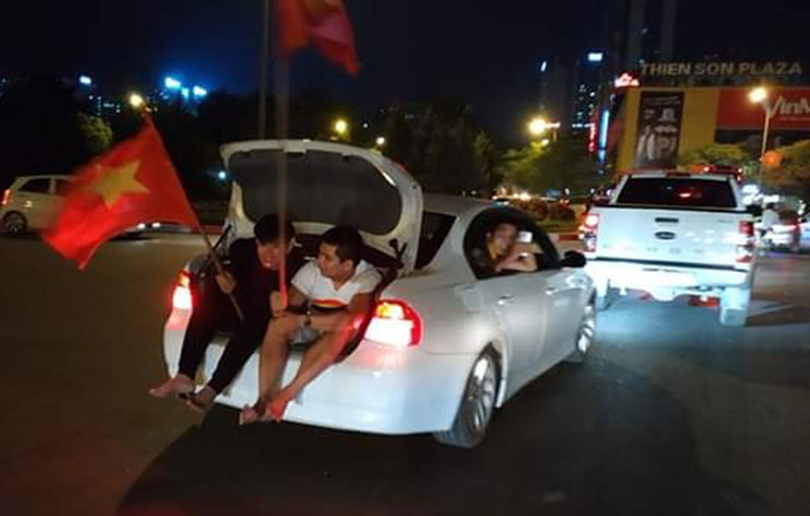 Cổ động viên ngồi sau cốp xe ô tô.