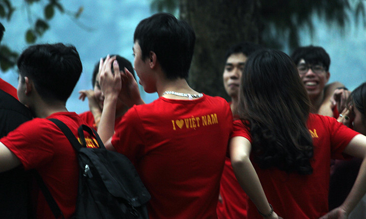 Cổ động viên khoác trên mình màu áo đỏ sao vàng, phía sau in chữ "Tôi yêu Việt Nam" để cổ động cho đội nhà.