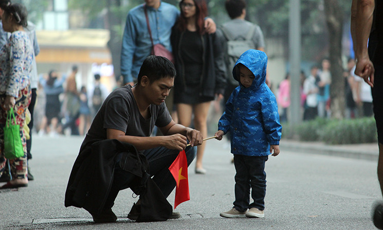 Một em bé được bố chuẩn bị cờ cổ vũ cho đội tuyển Việt Nam giành chiến thắng.