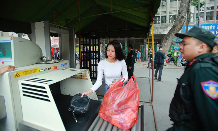 Các cổ động viên vào sân theo dõi trận đấu phải qua kiểm tra an ninh bên ngoài cửa.