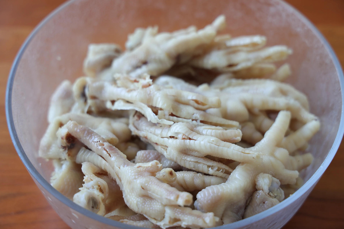 Bỏ chân gà đã róc xương vào âu. Chuẩn bị chanh, tỏi, ớt, rau mùi và mắm muối, nước tương tạo màu.