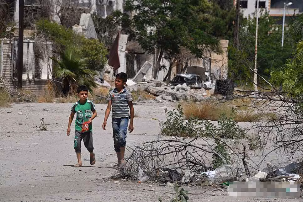 Hai bé trai đi lại trên đường phố ma ở al-Qaboun, phía đông Damascus.