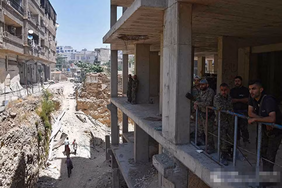 Nhóm lính Syria đứng trên ban công nhìn xuống cảnh quan đổ nát ở khu al-Qaboun.