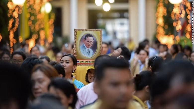Người dân Thái Lan đứng bên ngoài bệnh viện Siriraj và cầm ảnh chân dung Quốc vương Bhumibol trong dịp sinh nhật của ông năm 2015. Trước khi qua đời vào ngày 13/10/2016, Quốc vương Bhumibol từng nhiều lần nhập viện để điều trị bệnh nhiễm trùng đường hô hấp, tụ dịch quanh não và sưng phổi.