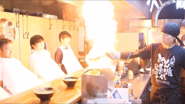 Cách đây 30 năm, hai cha con nhà Miyazawa đã mơ ước làm một điều gì đó đặc biệt. Vì thế, quán mì bốc lửa Menbakaichidai đã ra đời. Khi đến cửa hàng Menbakaichidai ở thành phố Kyoto, bạn sẽ thấy bề ngoài nó chẳng khác gì những cửa hàng bán mì ramen khác.