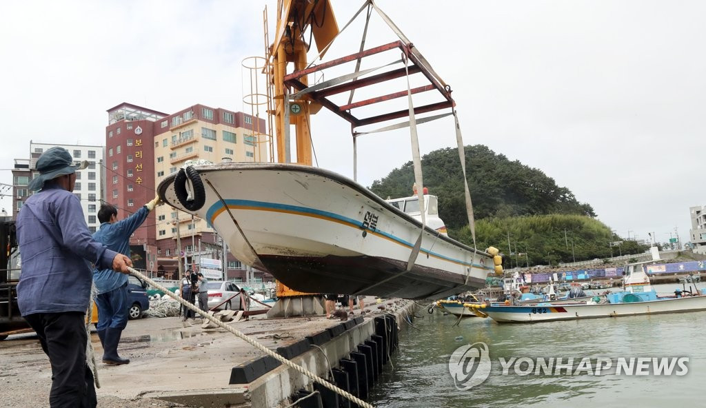 Giới chức cảnh báo, các khu vực bị ảnh hưởng chuẩn bị ứng phó với lũ lụt và sạt lở đất có thể xảy ra. Ảnh: Ngư dân chuyển những con thuyền lên đất liền tại thành phố cảng Busan trước khi bão Jangmi đổ bộ, ngày 9/8.