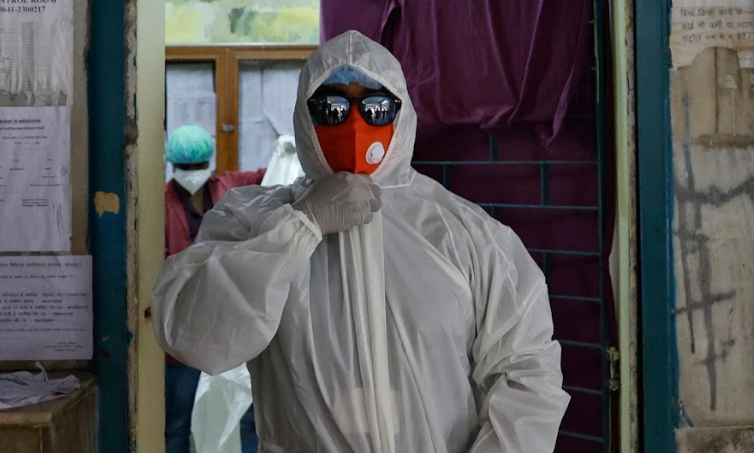 Sameer, nhân viên y tế 22 tuổi, mặc đồ bảo hộ và đeo kính râm như một thiết bị bảo vệ cá nhân để chuẩn bị đưa bệnh nhân COVID-19 từ phòng cấp cứu tới phòng chăm sóc đặc biệt.