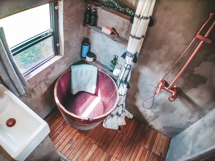 Một phòng tắm với bức tường bê tông phía bên trái. 