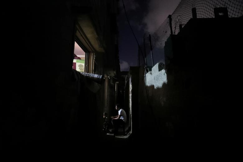 Người dân Palestine ngồi bên ngoài nhà của họ được chiếu sáng bằng chiếc đèn LED hôm 18/8.