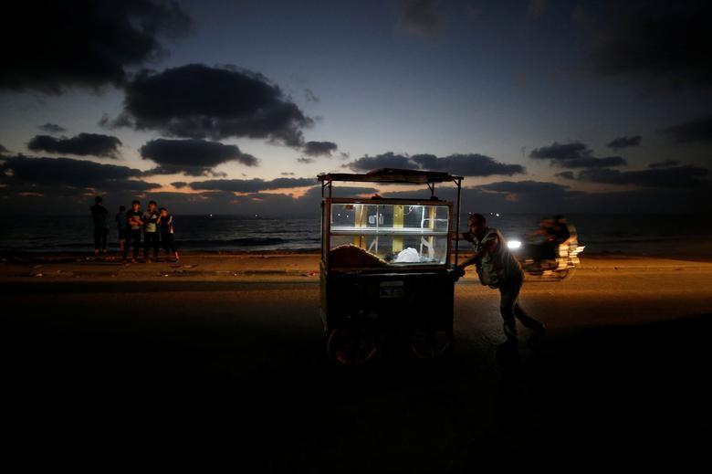 Một người bán hàng Palestine đẩy xe hàng trên đường phố Gaza khi màn đêm buông xuống hôm 18/8.