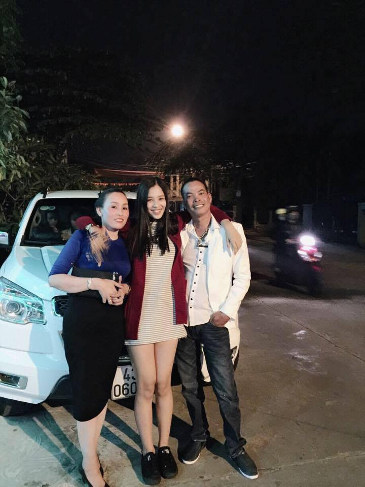 Trong bức ảnh chụp chung với bố mẹ, Tiểu Vy mặc chiếc váy kẻ phối với áo khoác đỏ khá trẻ trung, đúng độ tuổi học trò của cô.