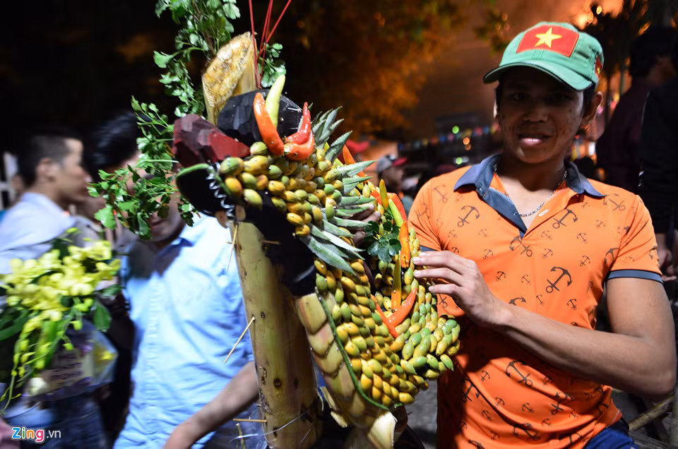 Một người tham gia tranh đồ cúng khoe "chiến lợi phẩm" là một phần hình con rồng được trang trí bằng trái cây đặt ngay bàn thờ ông Tiêu. Nhiều người giành được các loại đồ cúng như bánh, trái cây, hoa, giỏ hoa, kệ thờ bánh, trái... tin là những thứ sẽ mang lại may mắn nên họ mang về đặt lên bàn thờ trong nhà.