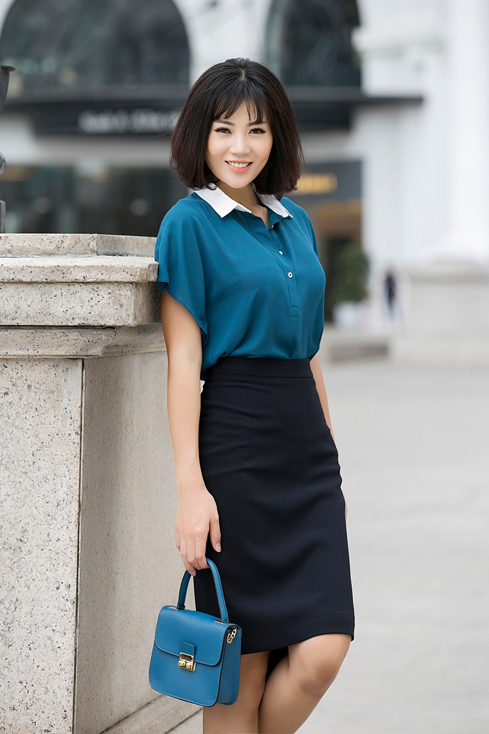 Thanh Hương chọn áo sơ mi xanh, chân váy đen và túi xanh làm tôn lên làn da trắng của cô.