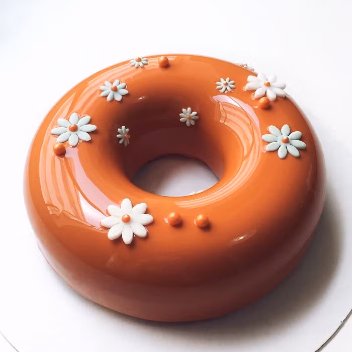 Bánh màu cam nổi bật hơn với những chiếc hoa trắng bằng socola.